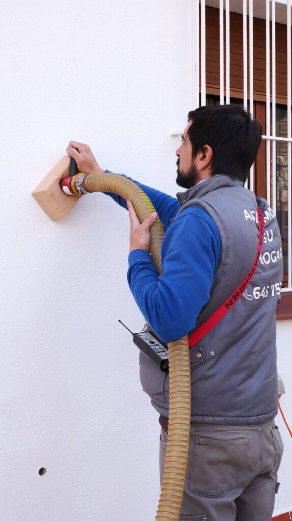 Persona con un tubo haciendo un asilamiento térmico insuflado en un gran edificio